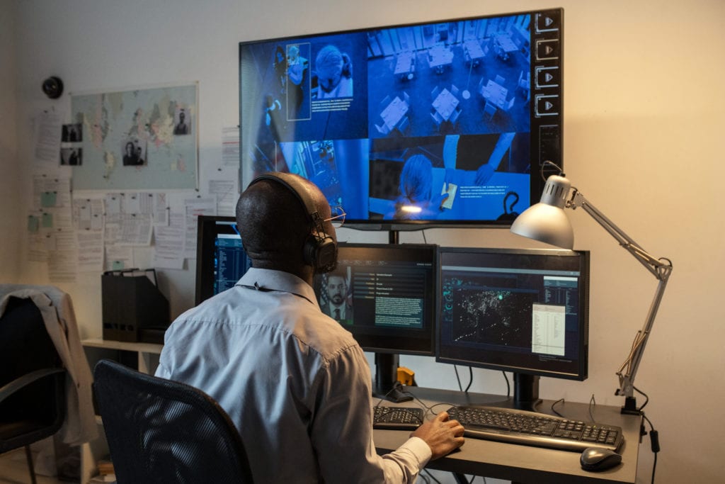 Young male agent of secret service watching record of crime in hotel lounge