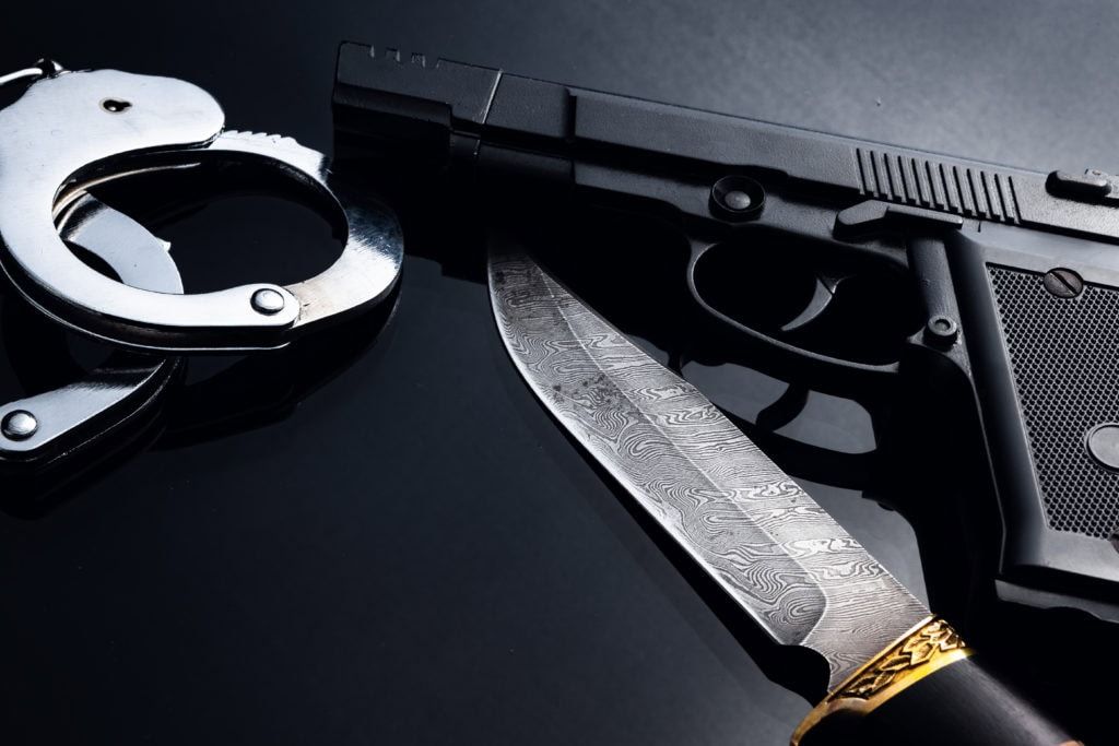 Gun, knife and handcuffs on black background