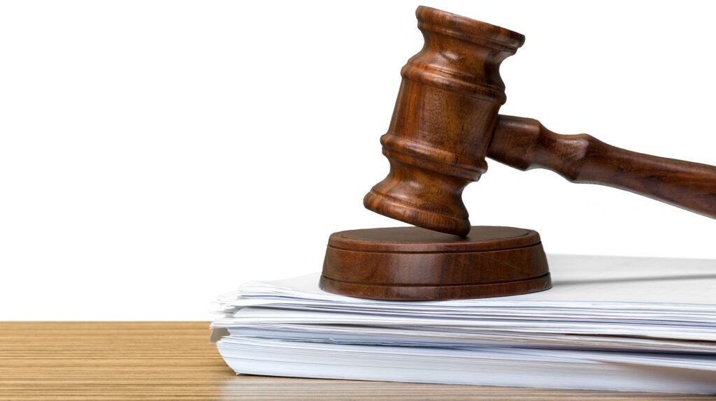Judge’s wooden gavel resting on a stack of court documents, representing bail hearings and surety responsibilities in Canadian criminal cases.