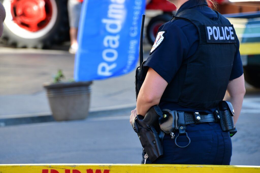 Police officer standing behind yellow barricade tape, representing background checks and law enforcement screening procedures in Ontario.
