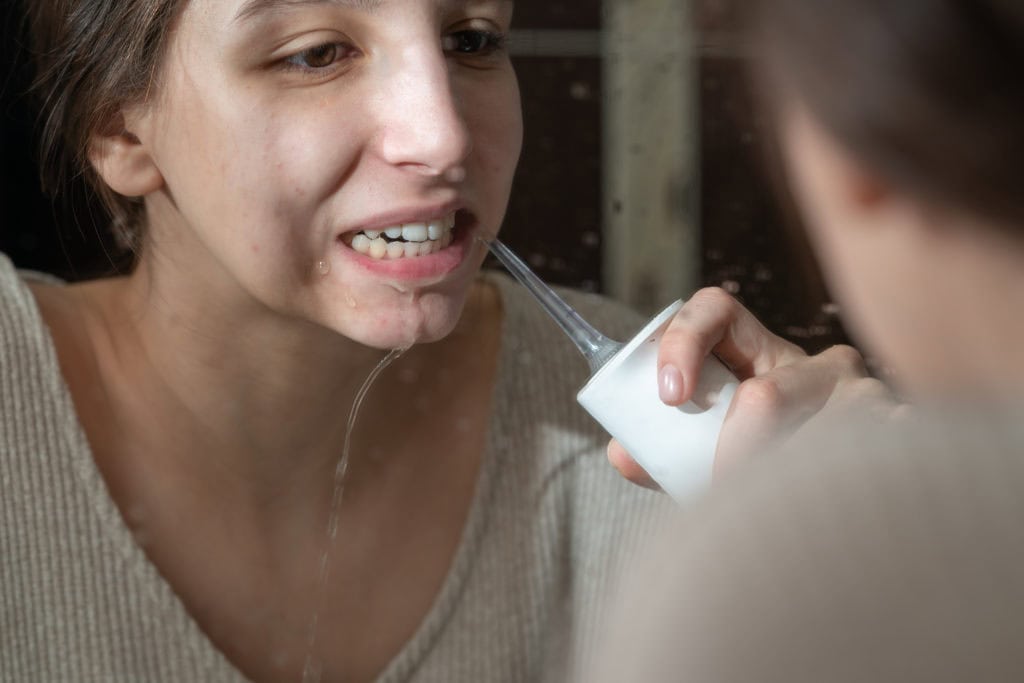 girl brushing her teeth with an irrigator